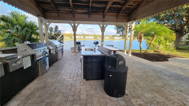 view of patio with area for grilling, a water view, and exterior kitchen