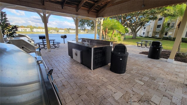 view of patio / terrace with exterior bar, an outdoor kitchen, and a water view