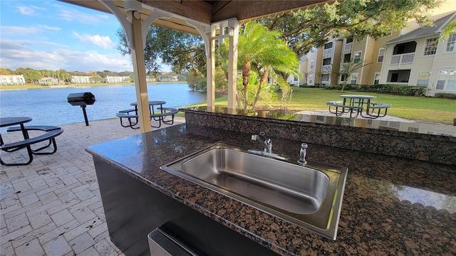 view of patio / terrace with a water view, a balcony, and sink