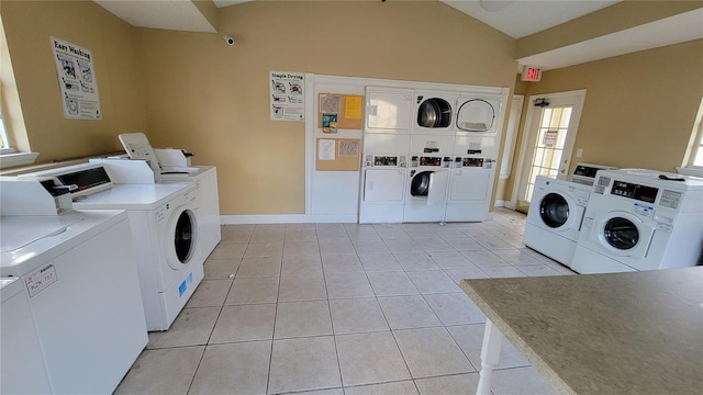 washroom with separate washer and dryer, light tile floors, and stacked washing maching and dryer