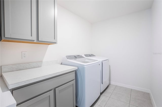 laundry area with cabinets, light tile patterned floors, and washer and clothes dryer