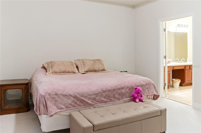 bedroom featuring sink, light colored carpet, and ensuite bath