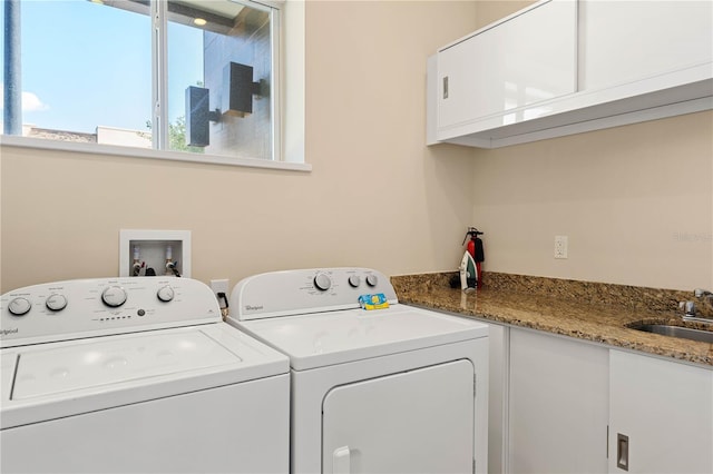 clothes washing area with cabinets, separate washer and dryer, and sink