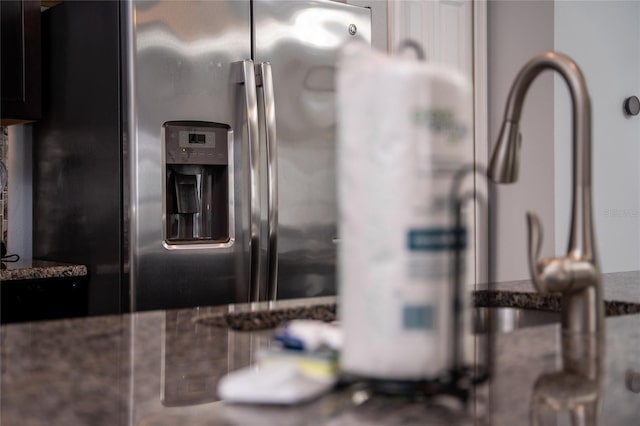 room details with stainless steel refrigerator with ice dispenser and dark stone countertops