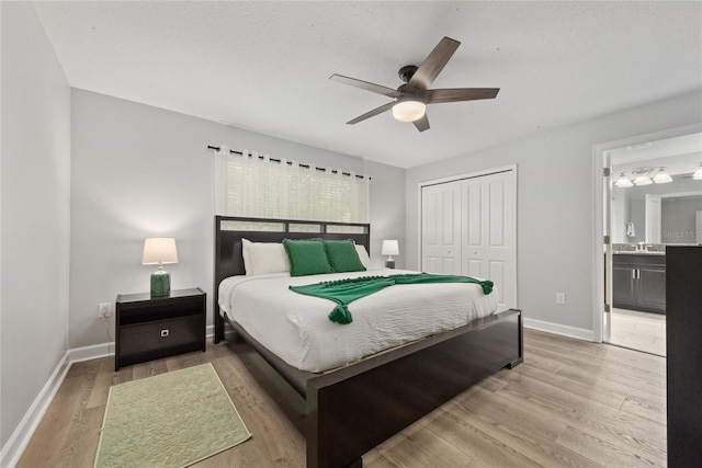 bedroom with a closet, ceiling fan, connected bathroom, and light hardwood / wood-style floors