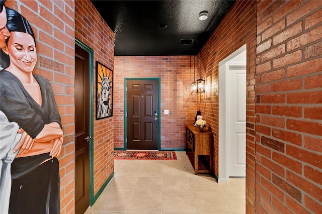 hallway featuring brick wall, a textured ceiling, and light tile floors