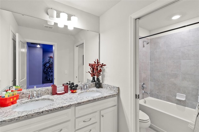 full bathroom with toilet, dual bowl vanity, and tiled shower / bath