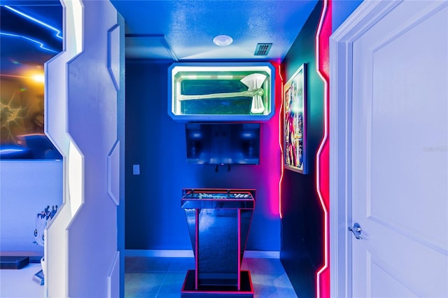 game room featuring a textured ceiling and dark tile flooring