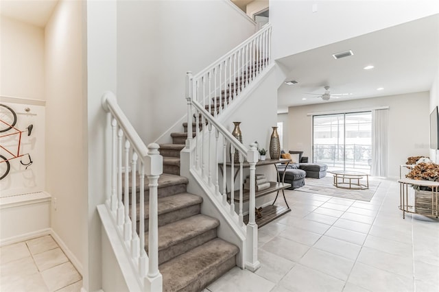 stairway featuring ceiling fan, tile patterned flooring, and a high ceiling