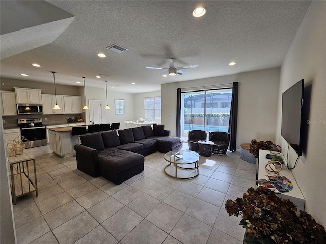 living room featuring a textured ceiling, ceiling fan, and light tile patterned flooring