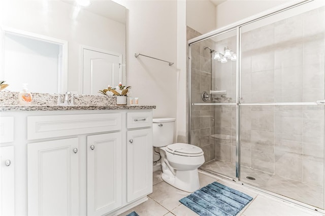 bathroom featuring toilet, vanity, tile patterned floors, and a shower with shower door