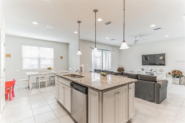 kitchen with stainless steel dishwasher, light stone counters, sink, and a kitchen island with sink