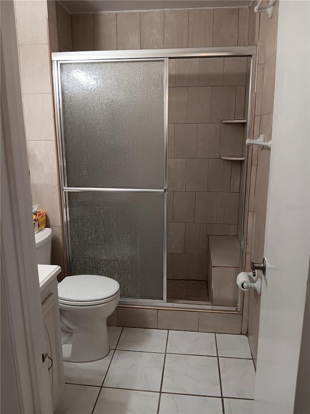 bathroom featuring toilet, marble finish floor, a shower stall, and vanity