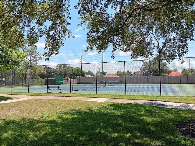 view of tennis court featuring a yard and fence