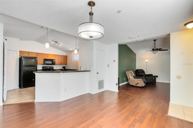 kitchen featuring lofted ceiling, light wood-type flooring, ceiling fan, and black appliances