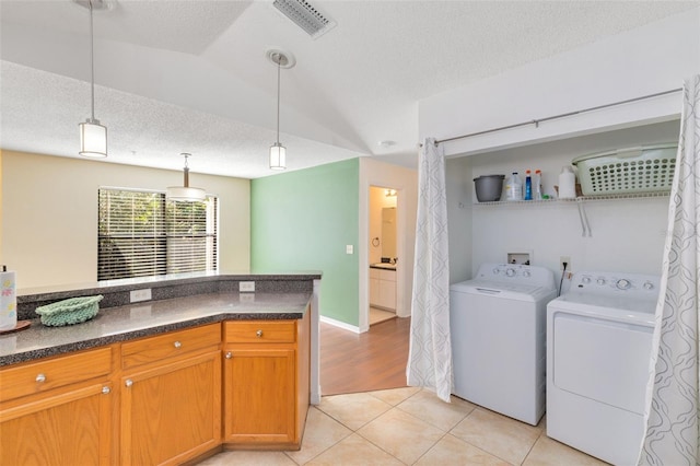 interior space with hookup for a washing machine, a textured ceiling, washer and dryer, and light wood-type flooring