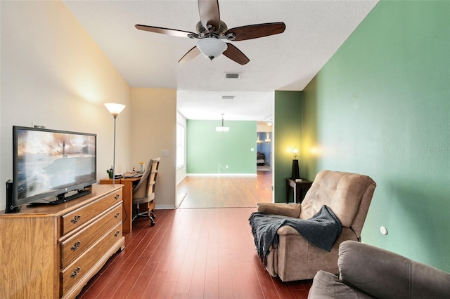 living room featuring ceiling fan, dark wood-type flooring, and a textured ceiling