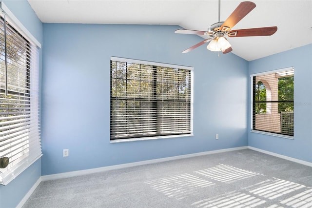 empty room featuring plenty of natural light, ceiling fan, vaulted ceiling, and light colored carpet