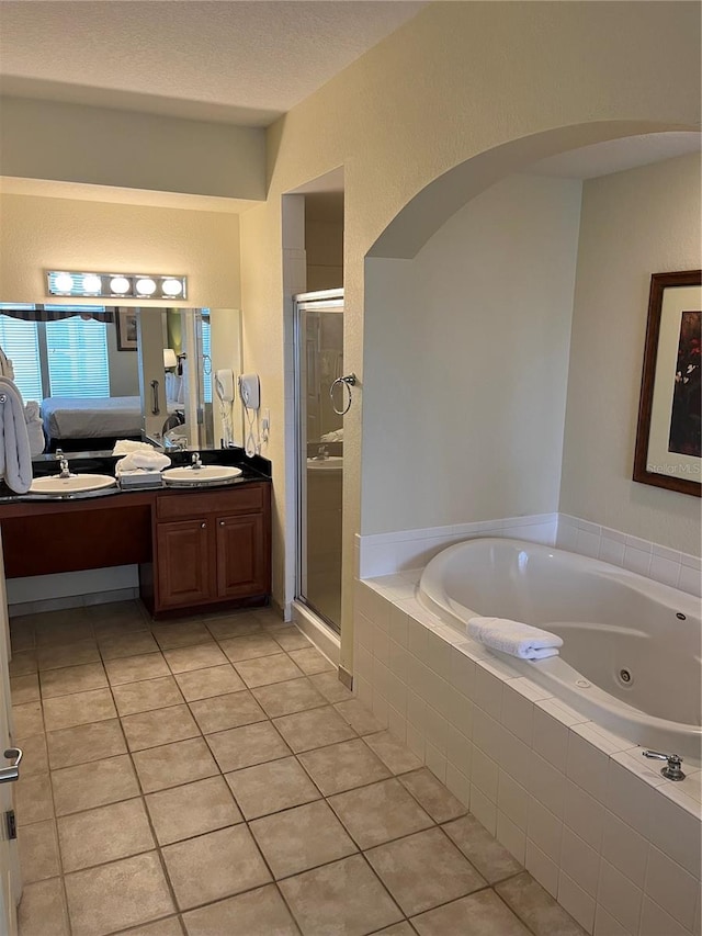 bathroom featuring a textured ceiling, tile floors, dual vanity, and plus walk in shower