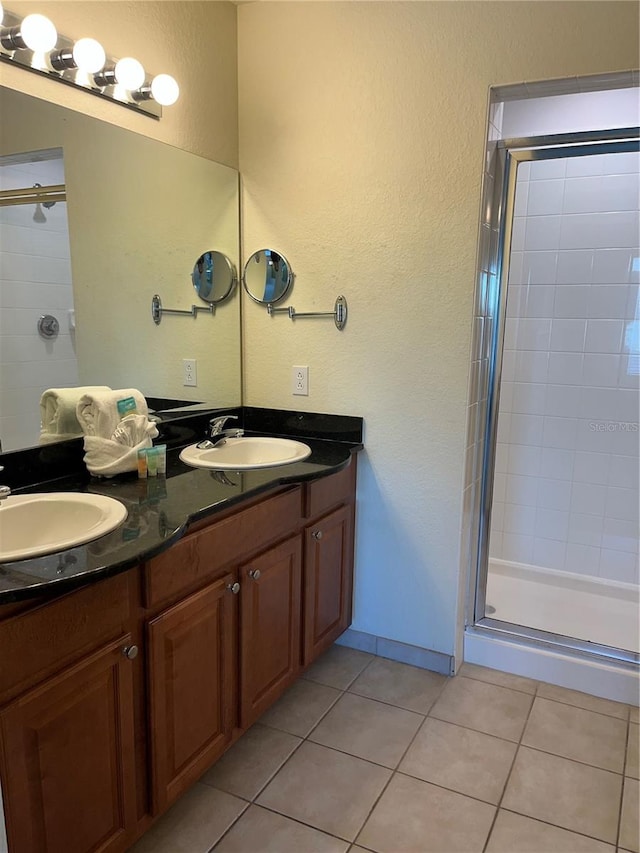 bathroom with double vanity, tile flooring, and a shower with shower door