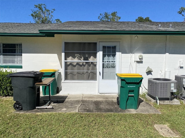 view of exterior entry featuring a lawn and central air condition unit