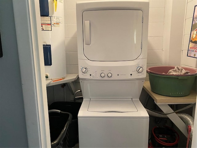 washroom with electric water heater and stacked washer and dryer