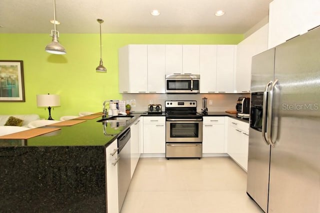 kitchen with dark countertops, appliances with stainless steel finishes, white cabinetry, and a sink