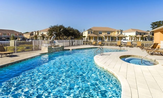 pool with a residential view, a patio, a hot tub, and fence