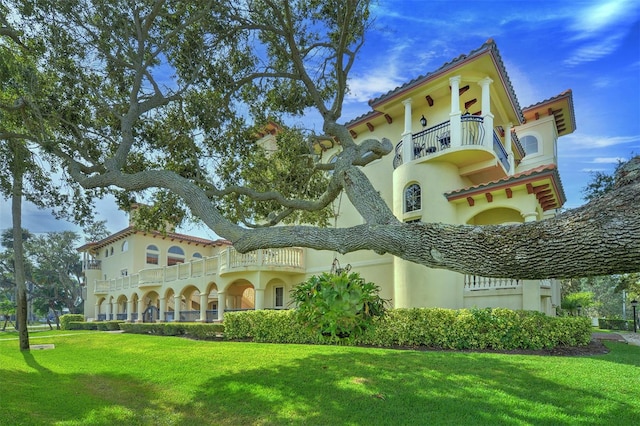 back of property featuring a balcony and a lawn