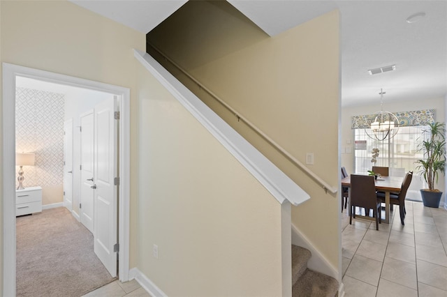 stairs featuring a notable chandelier and light colored carpet