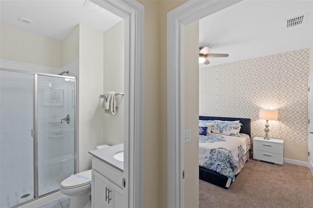 carpeted bedroom with ensuite bath and ceiling fan