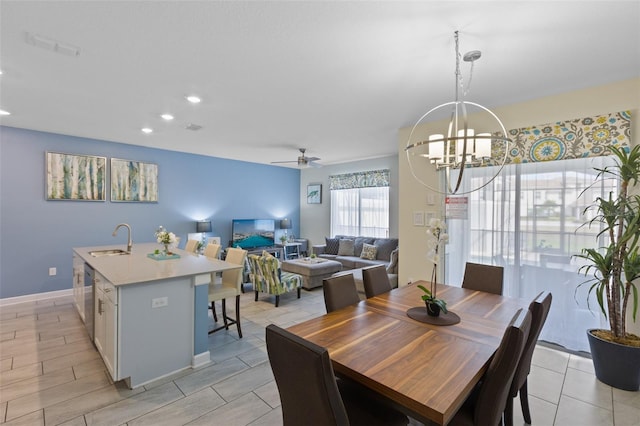 tiled dining area with ceiling fan with notable chandelier and sink