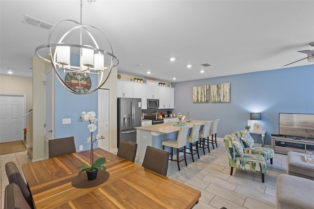 dining area featuring light tile flooring and ceiling fan with notable chandelier