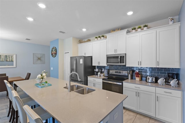 kitchen with backsplash, an island with sink, stainless steel appliances, and a breakfast bar