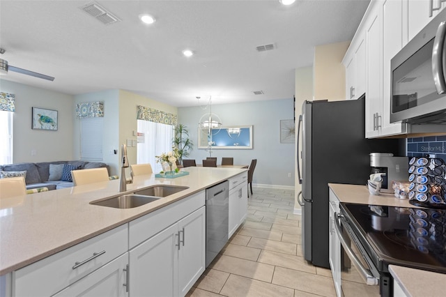 kitchen with white cabinetry, a notable chandelier, appliances with stainless steel finishes, sink, and light tile floors