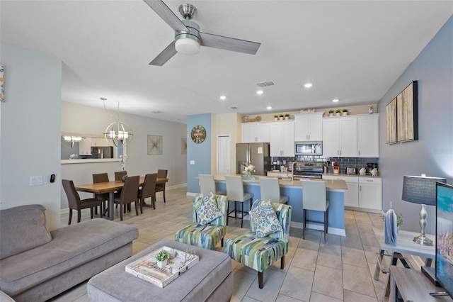 tiled living room with ceiling fan with notable chandelier