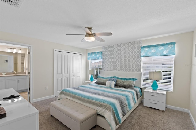 bedroom with ceiling fan, sink, light carpet, ensuite bath, and a closet