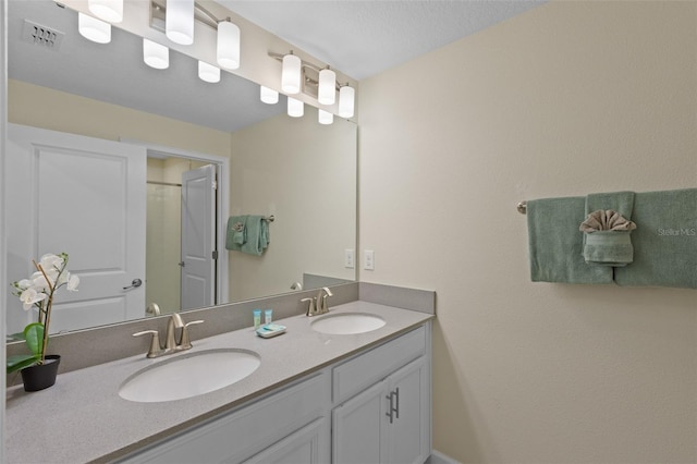 bathroom with a textured ceiling and dual bowl vanity