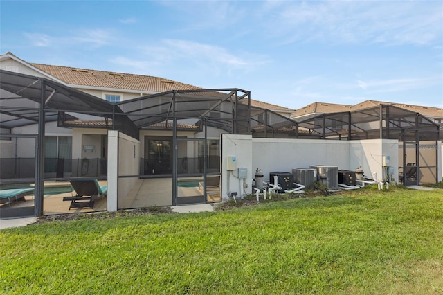 back of house featuring glass enclosure, a fenced in pool, and a lawn