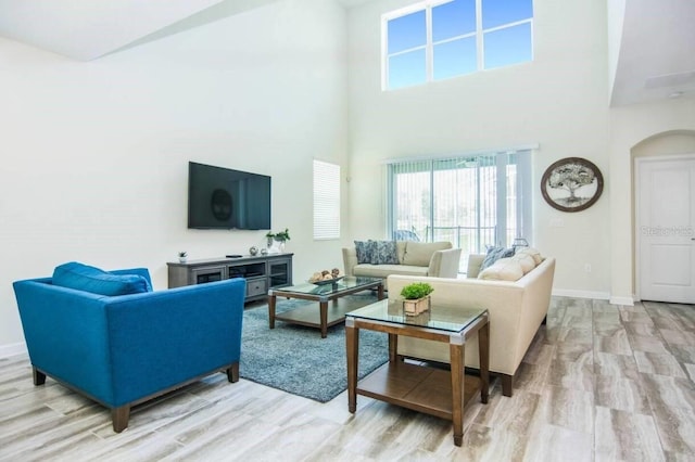 living room with a towering ceiling and light wood-type flooring