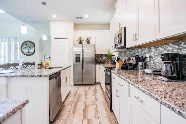 kitchen featuring hanging light fixtures, backsplash, sink, stainless steel appliances, and white cabinets