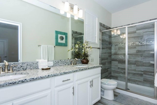 bathroom featuring double sink vanity, toilet, and an enclosed shower