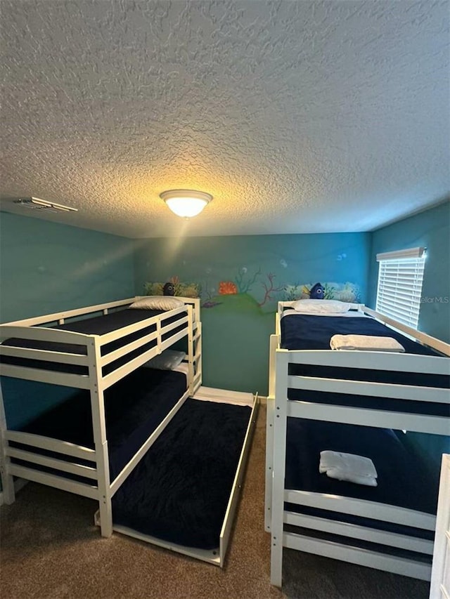 bedroom with a textured ceiling and dark carpet