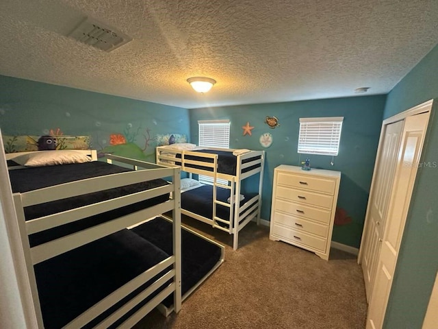 bedroom with a closet, dark colored carpet, and a textured ceiling