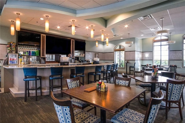 dining space featuring indoor bar, a drop ceiling, and dark wood-type flooring