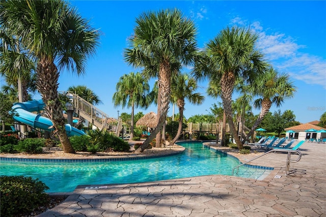 view of pool with a water slide and a patio area