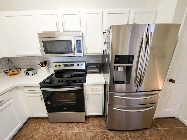 kitchen with stainless steel appliances, tasteful backsplash, light countertops, white cabinetry, and dark tile patterned flooring