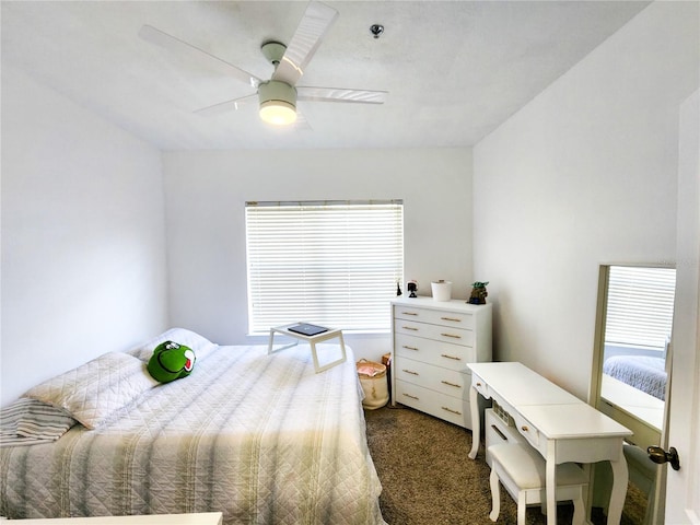 bedroom with multiple windows, dark colored carpet, and a ceiling fan