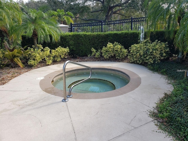 view of swimming pool with an in ground hot tub and fence