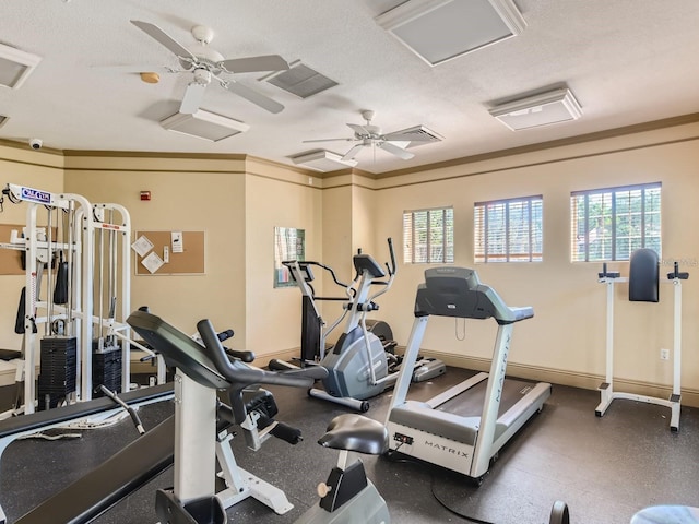 gym featuring attic access, a textured ceiling, baseboards, and crown molding